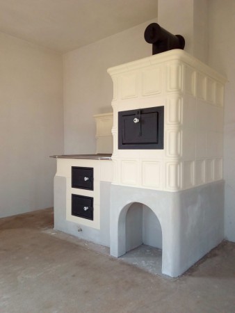 Kachlový sporák s moderním topeništěm UMWELT PLUS. Sokl je předskočený dopředu a dává tak sporáku rustikální vzhled. Kachle ve veelmi pěkné glazůře "slonová kost matná". Stavba vznikla ve spolupráci s BH Kamnářství.